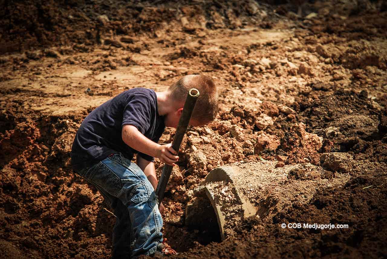 Caritas Community kid shoveling dirt