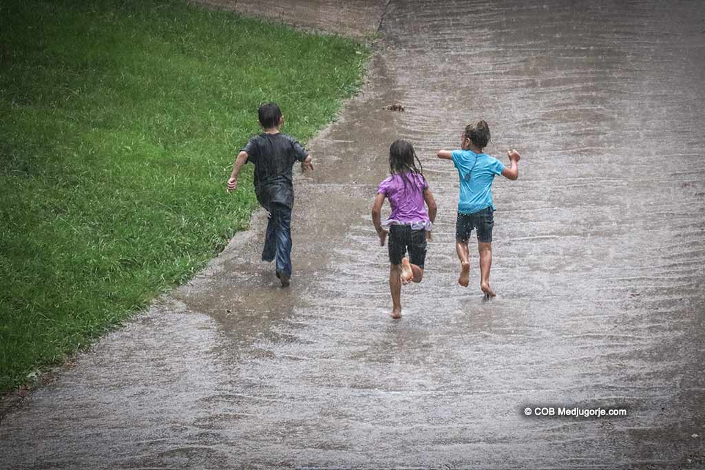 Caritas kids playing in the rain, August 19, 2019